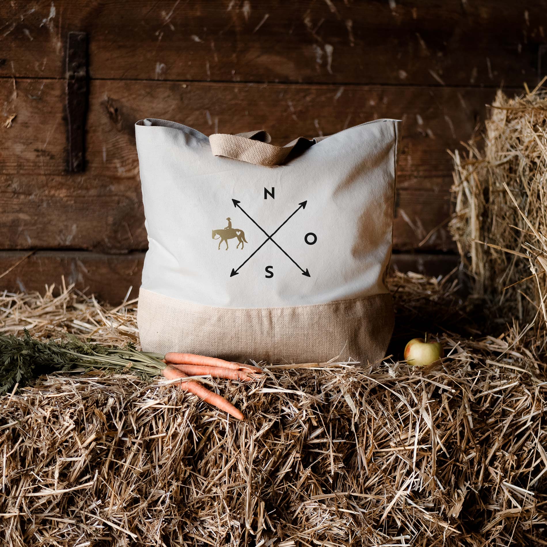 Helle Jutetasche mit schwarz-goldenem Motiv auf Stroh im Stall 