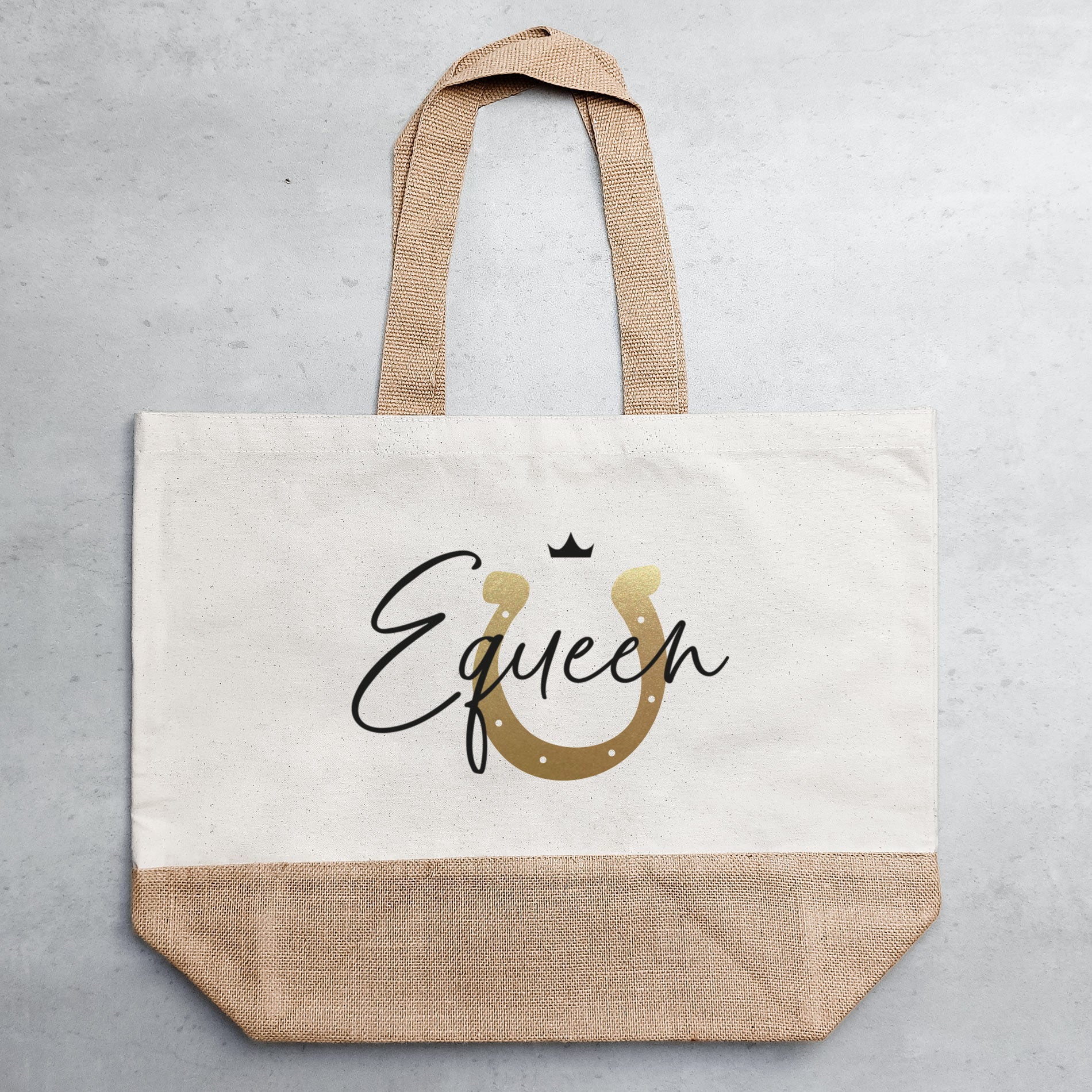 Helle Jutetasche mit schwarz-goldenem Motiv auf grauem Untergrund